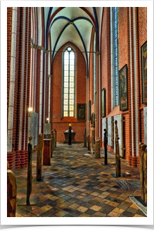 Side aisle showing local artwork and a stone crypt at the end.